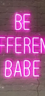 Neon pink "Be Different Babe" sign on brick wall.